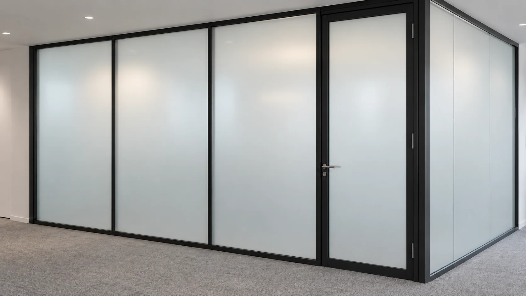 Frosted meeting-room glass panels and door in slim black frames, viewed from an office corridor.