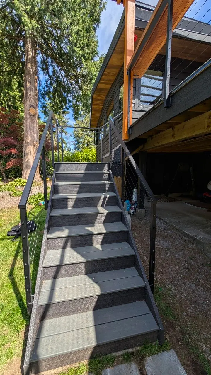 Looking up the composite stairs between matte black cable stair guards, cables running parallel to the stair rake