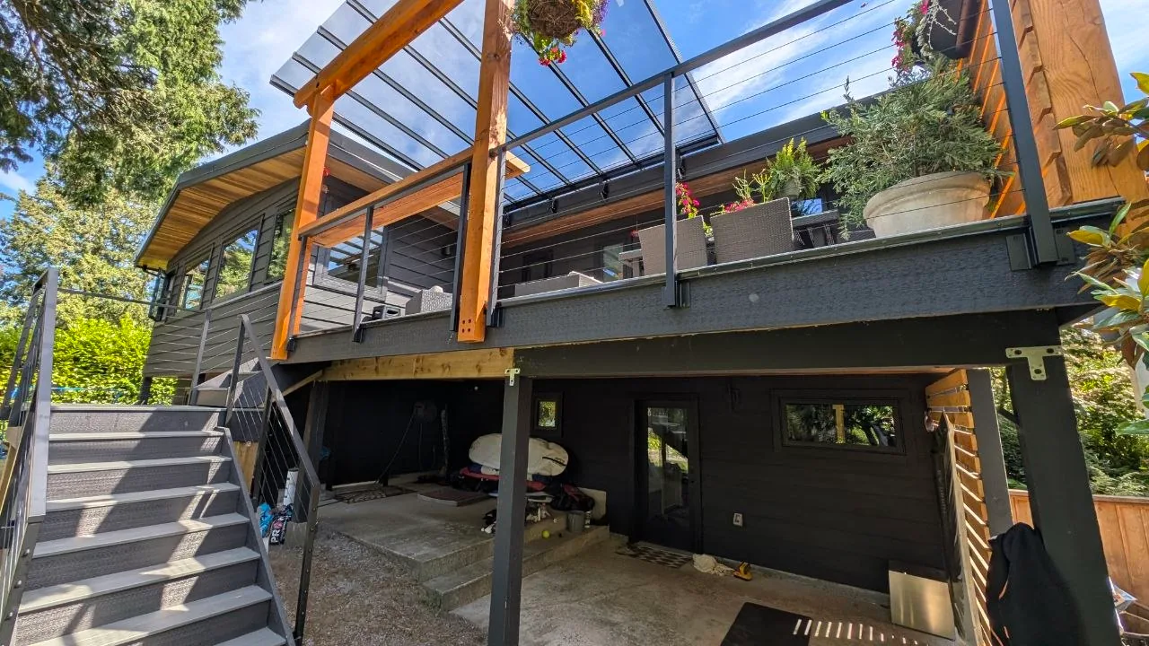Fascia-mounted cable railing posts along the upper deck edge, seen from the covered patio below
