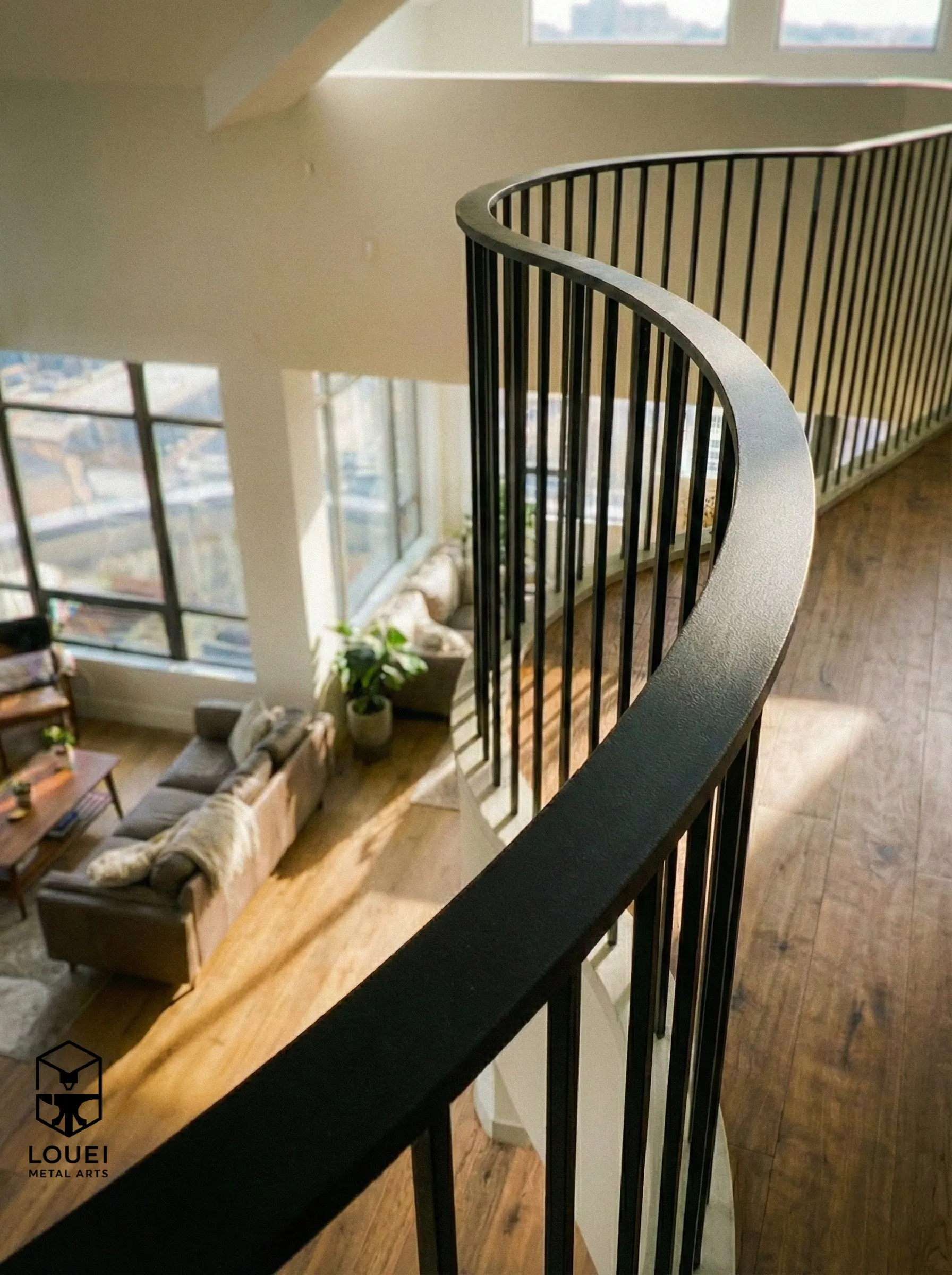 Curved black picket guardrail overlooking loft living room in a Vancouver condo