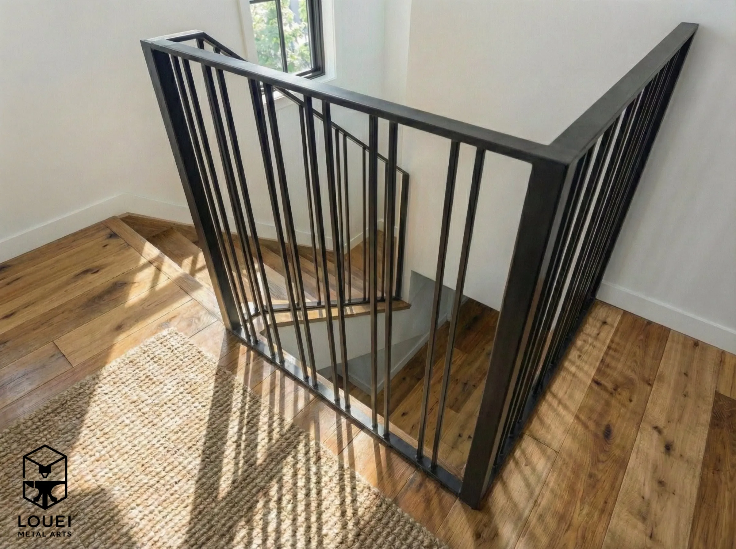 Square stair opening enclosed with black picket railing in a Vancouver renovation