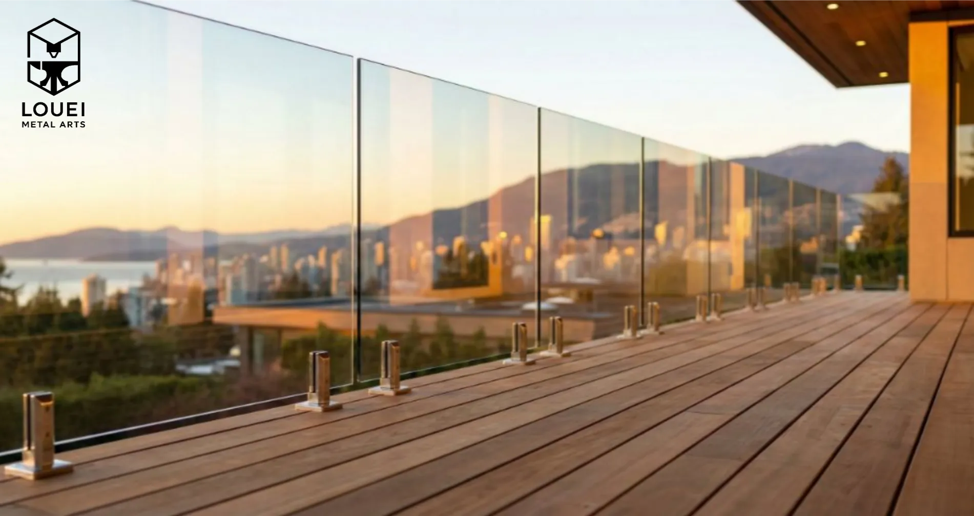 Frameless glass deck railing secured with stainless steel spigots along a wood rooftop terrace with a city and mountain view.