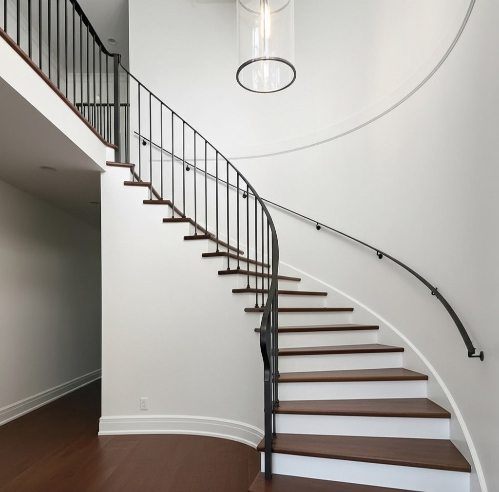 Custom black powder-coated wrought iron picket railing with curved vertical pickets on walnut treads — heritage-compatible design by LOUEI Metal Arts